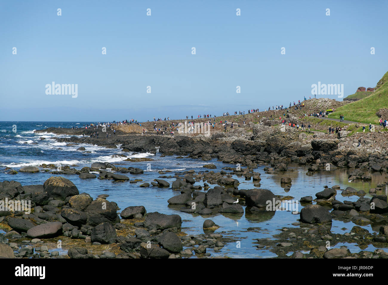 View on the Giant`s Causeway coast stretching out to the Atlantic ocean occupied by tourists and visitors Bushmills Antrim Northern Ireland Stock Photo